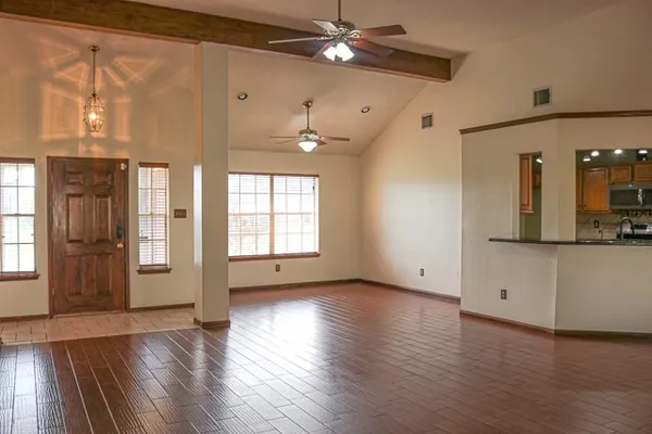 a view of an empty room with window and wooden floor