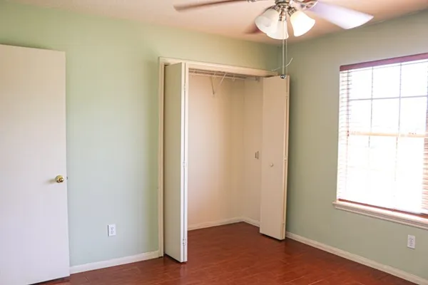 a view of an empty room with window and wooden floor