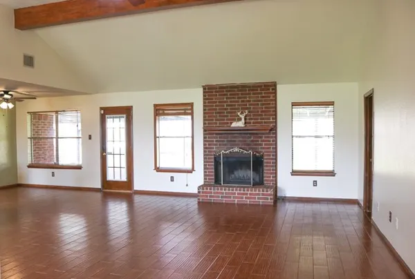 a view of an empty room with a fireplace and wooden floor