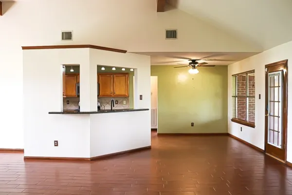 a view of an empty room with wooden floor and a window
