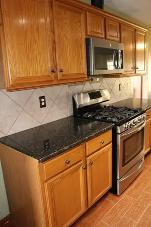 a kitchen with granite countertop white cabinets and stainless steel appliances