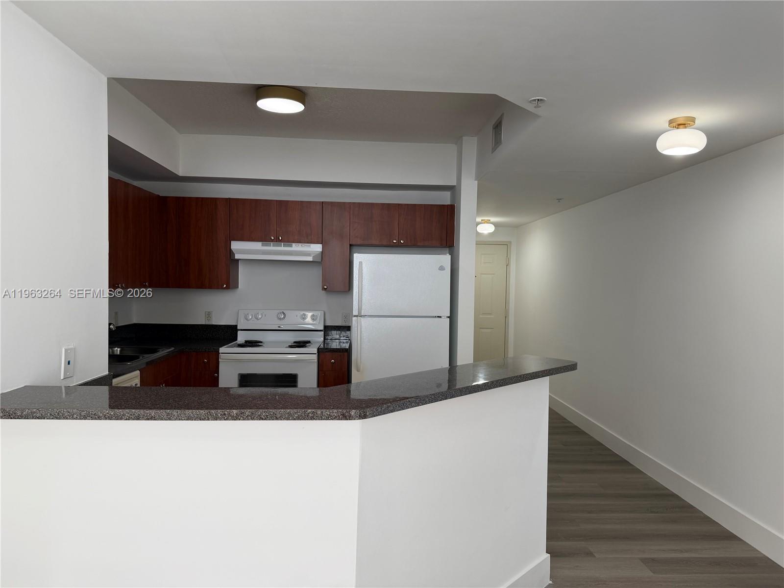 115 Southwest 11th Street, Unit 805 Miami, FL 33130 - Photo 4 of 13 a kitchen with stainless steel appliances granite countertop a sink and a refrigerator