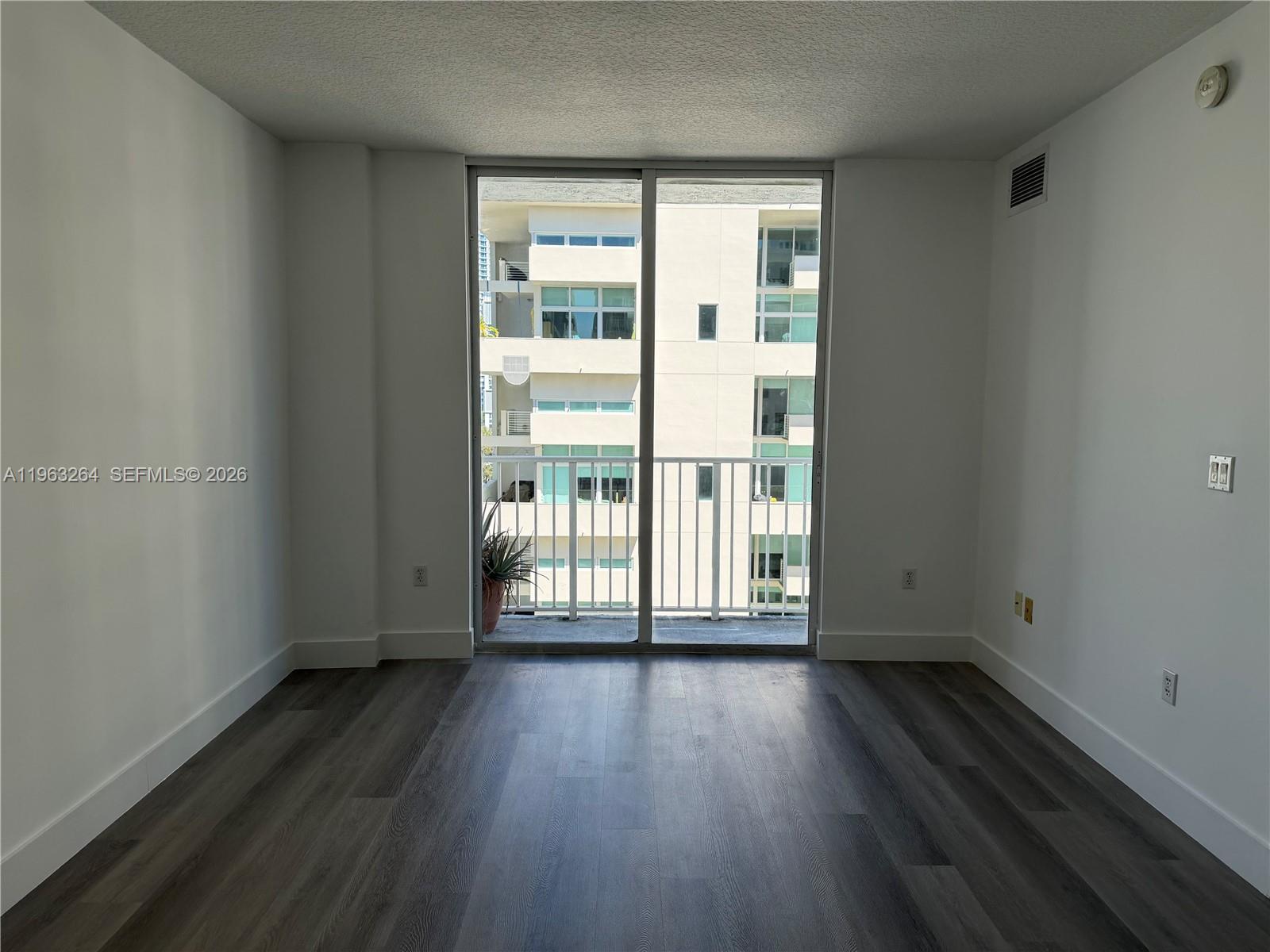 115 Southwest 11th Street, Unit 805 Miami, FL 33130 - Photo 5 of 13 wooden floor in an empty room with a window