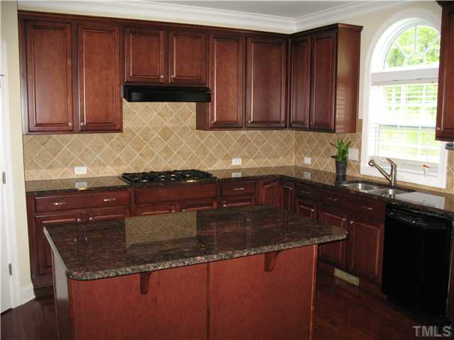 1614 Pattersons Mill Road Durham, NC 27703 - Photo 7 of 16 Island kitchen with stain cabinets, granite countertops, tile backsplash, GE Profile gas cooktop, built-in oven/microwave, dishwasher, refrigerator and hardwood floors.