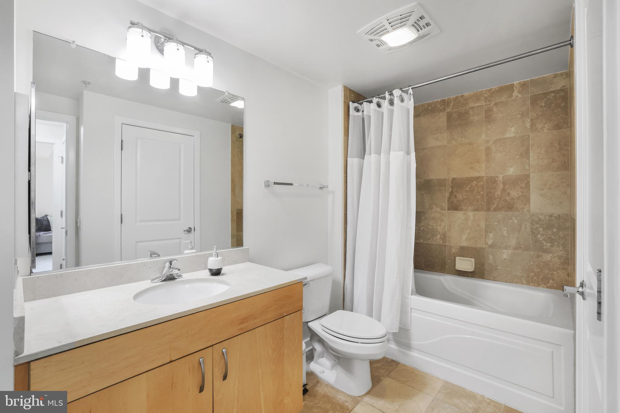 475 K Street Northwest, Unit 920 Washington, DC 20001 - Photo 15 of 25 a bathroom with a bathtub shower sink vanity mirror and toilet