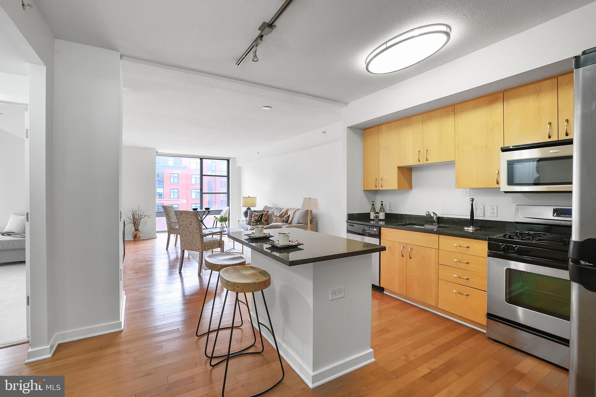 475 K Street Northwest, Unit 920 Washington, DC 20001 - Photo 3 of 25 a kitchen with stainless steel appliances granite countertop a stove a sink dishwasher a microwave oven and a dining table with wooden floor