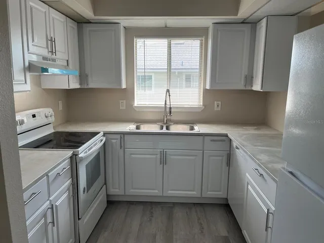 a kitchen with granite countertop a sink stove and cabinets