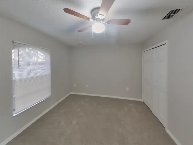 an empty room with windows and fan