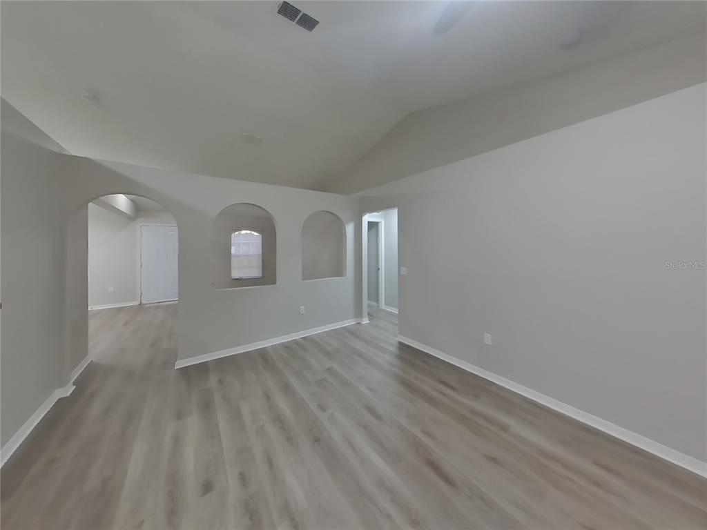 Undisclosed Address Spring Hill, FL 34609 - Photo 2 of 17 an empty room with wooden floor and mirror