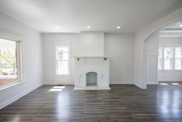an empty room with wooden floor windows and fireplace