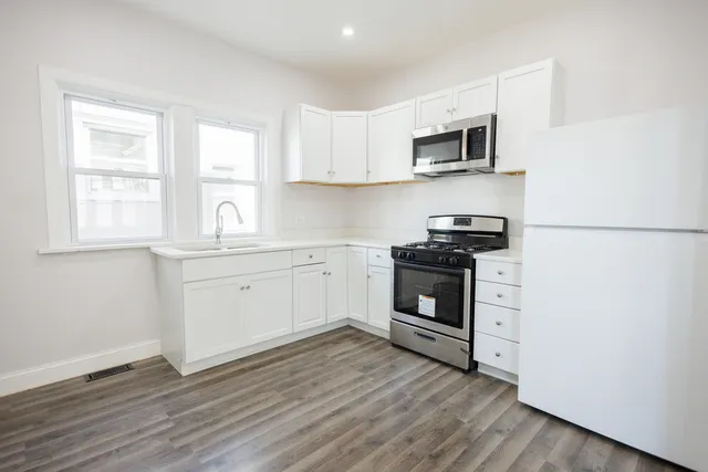 a view of kitchen with granite countertop white cabinets and black stainless steel appliances