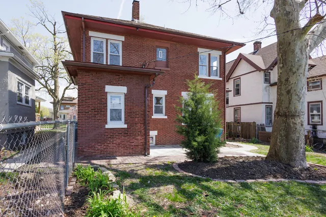 a view of a house with brick walls and a yard with plants
