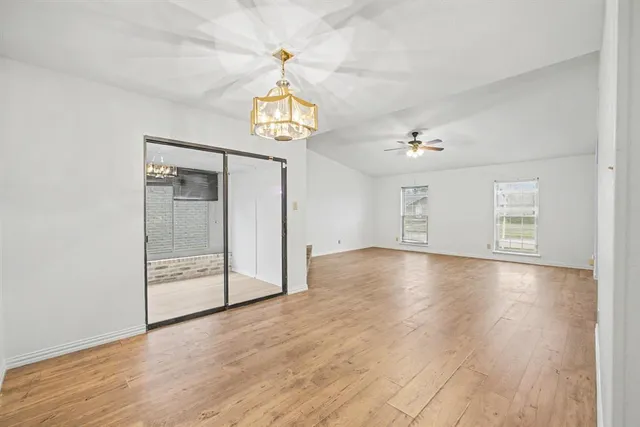 an empty room with wooden floor and chandelier
