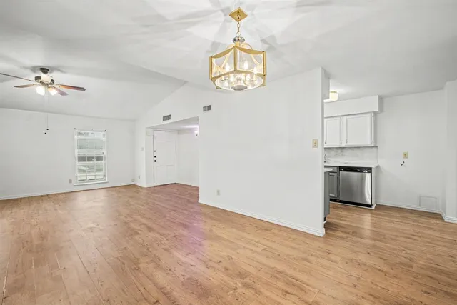 an empty room with wooden floor cabinet and windows