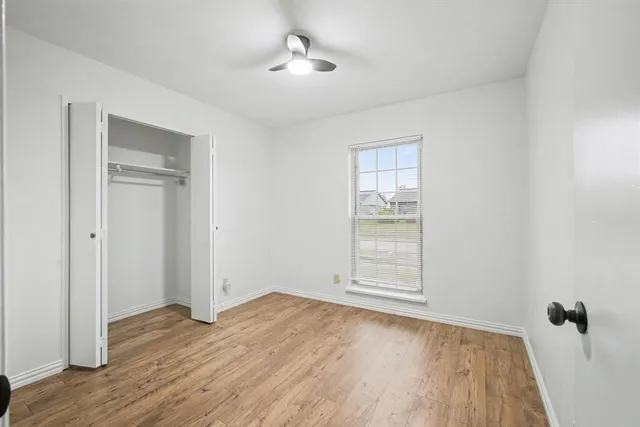 an empty room with wooden floor cabinet and windows
