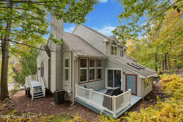 a view of a house with wooden fence and large trees