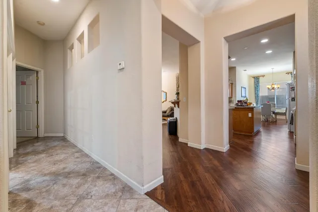 a view of a hallway with wooden floor a chandelier and a bathroom