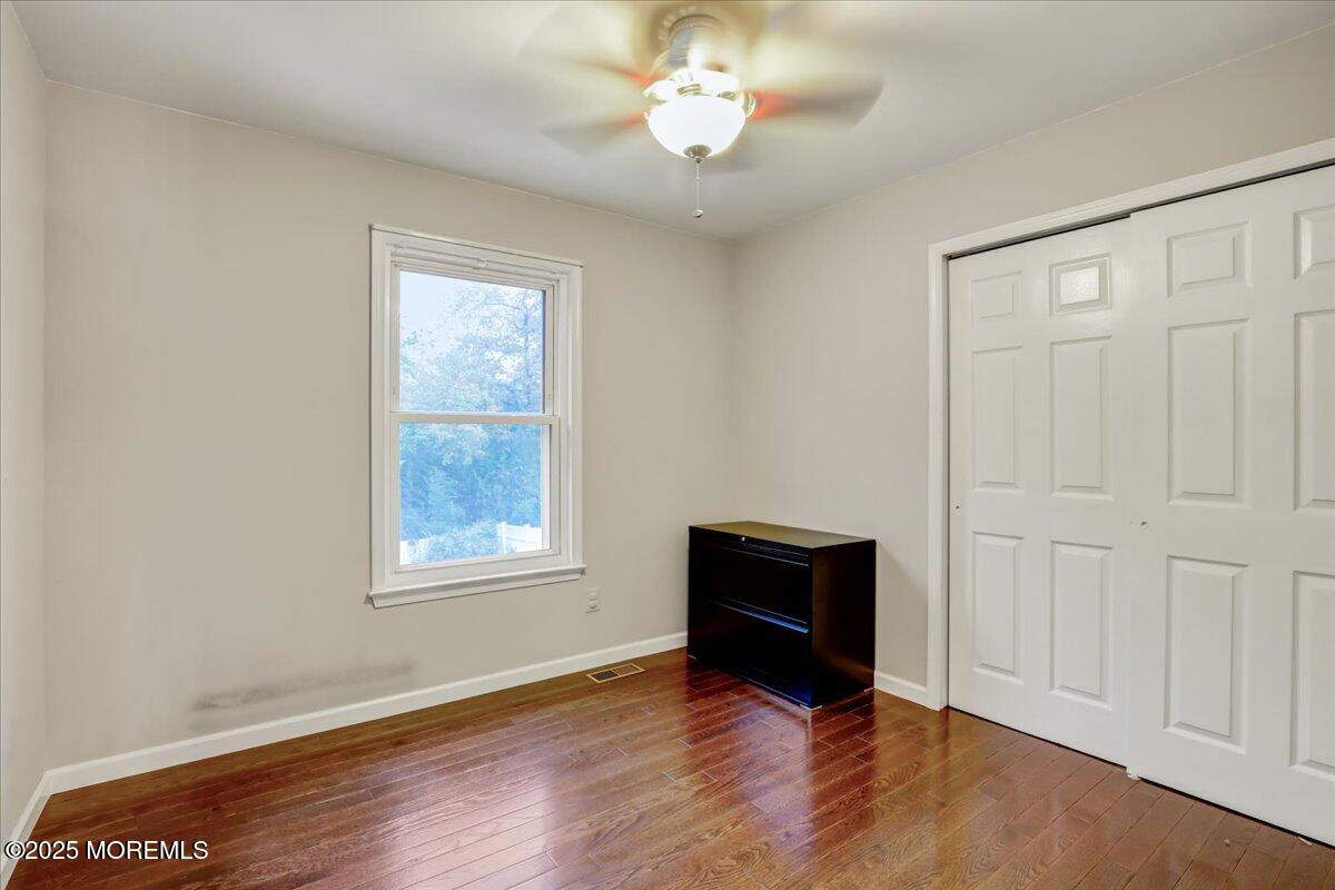7 Hawk Court Howell, NJ 07731 - Photo 24 of 32 an empty room with wooden floor ceiling fan and windows