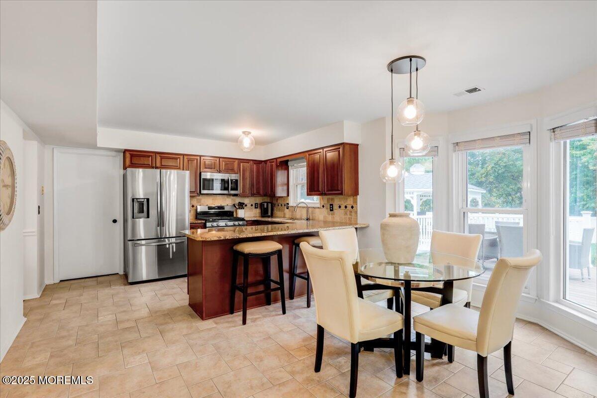 7 Hawk Court Howell, NJ 07731 - Photo 9 of 32 a kitchen with stainless steel appliances kitchen island granite countertop a table chairs refrigerator and a sink