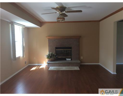 619 Lloyd Road Aberdeen, NJ 07747 - Photo 5 of 8 a living room with a fireplace and a ceiling fan