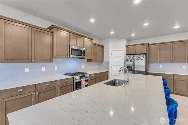 a kitchen with stainless steel appliances a sink dishwasher stove top oven and cabinets with wooden floor
