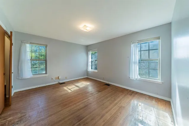 a view of an empty room with wooden floor and closet