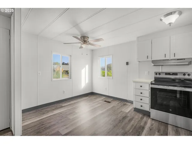 a view of an empty room with a kitchen and a window