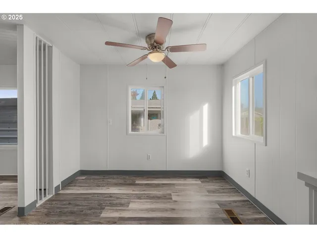 a view of empty room with wooden floor and fan