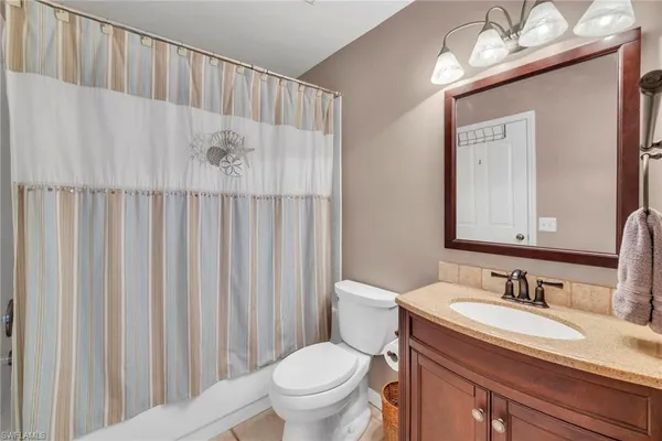 a bathroom with a granite countertop sink and a toilet