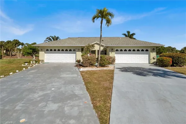 a front view of a house with a yard and palm trees