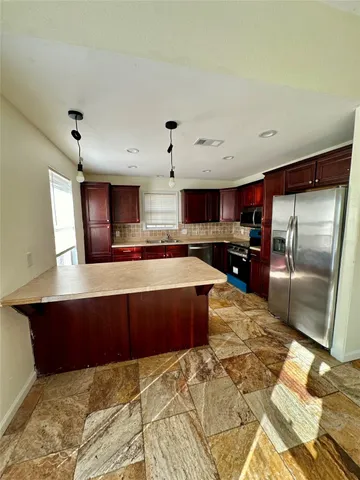 a large kitchen with kitchen island granite countertop a refrigerator and a sink