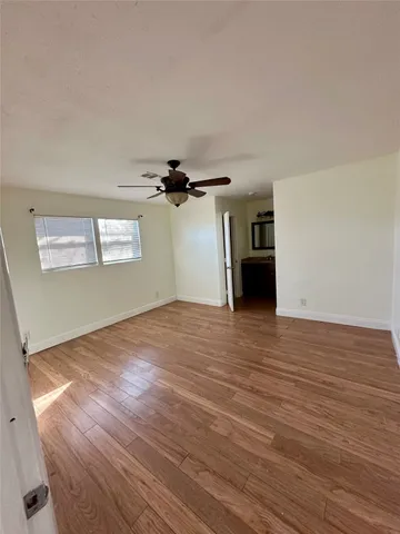 a view of a room with wooden floor and ceiling fan