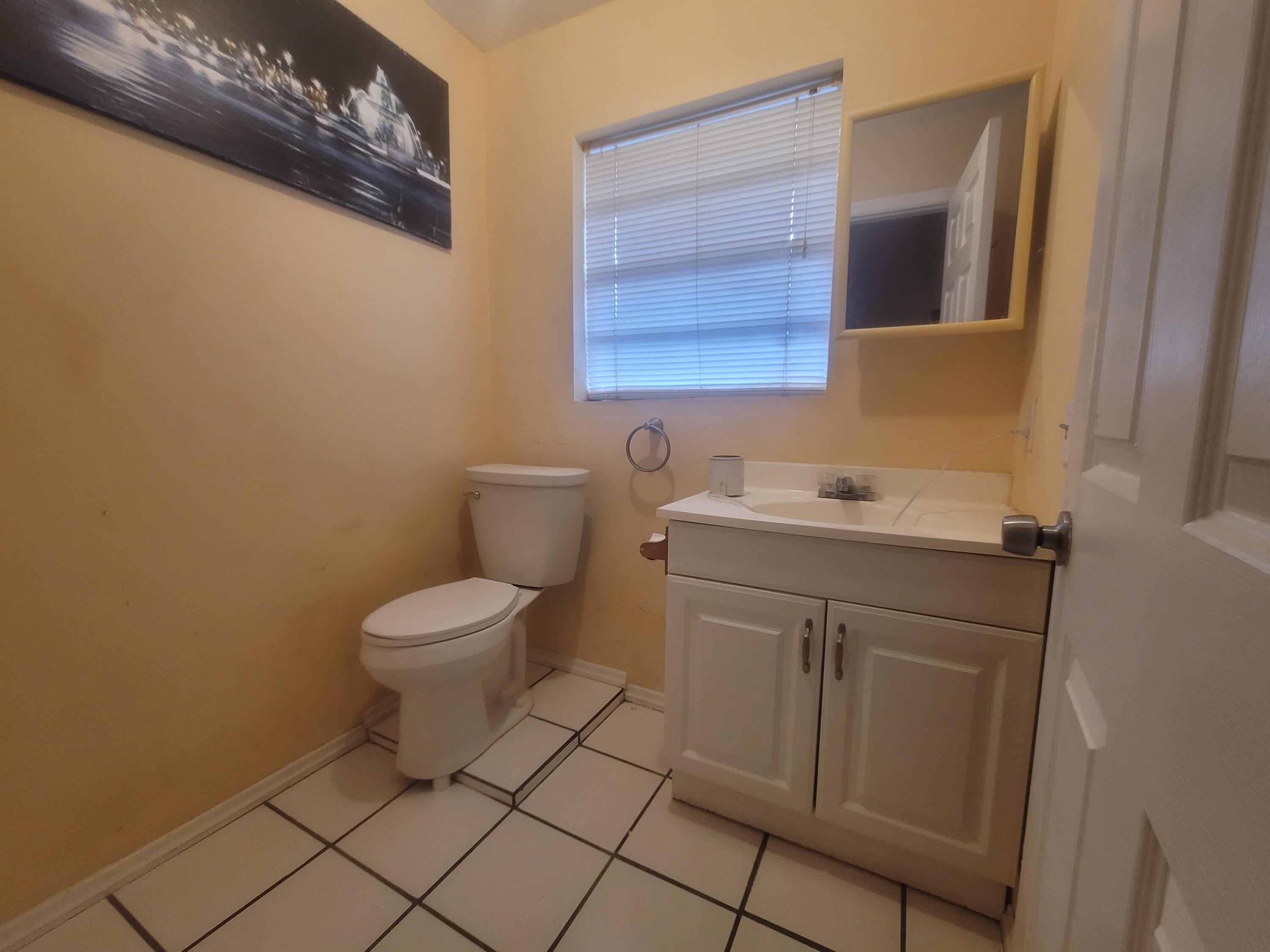 15664 N Road, Unit A Loxahatchee Groves, FL 33470 - Photo 13 of 16 a bathroom with a toilet sink and mirror
