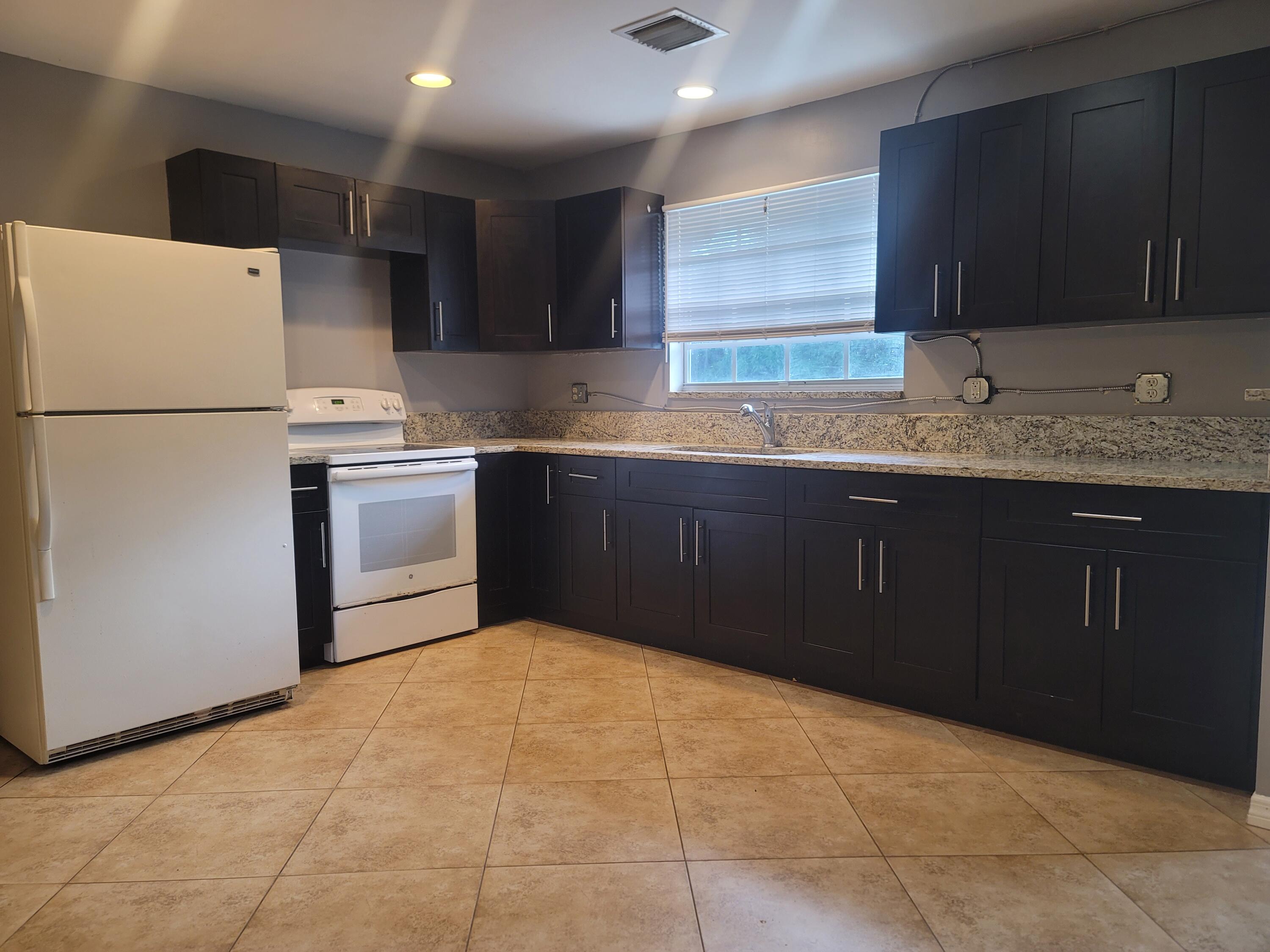 15664 N Road, Unit A Loxahatchee Groves, FL 33470 - Photo 10 of 16 a kitchen with granite countertop a sink and a stove top oven