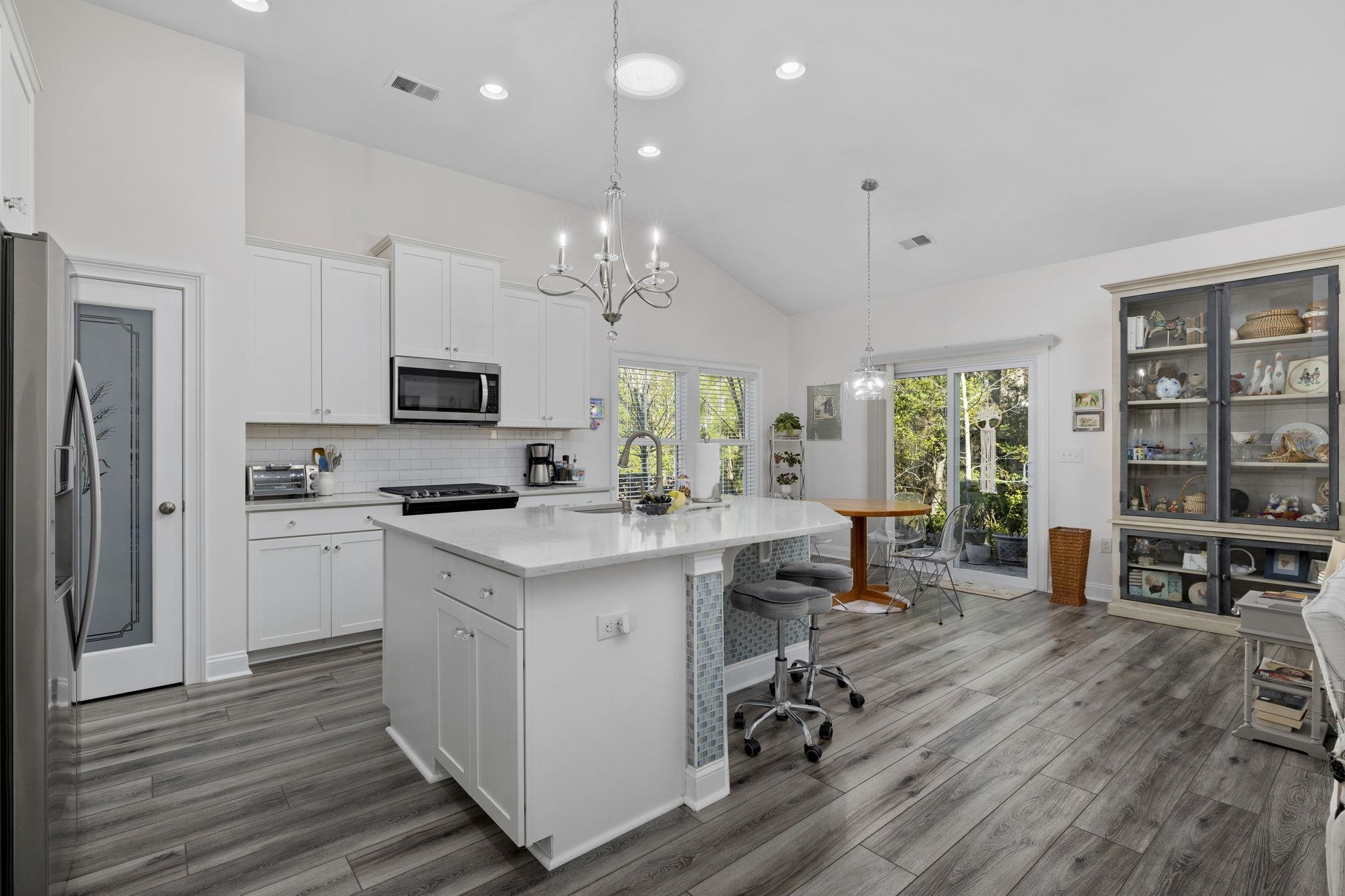 1704 Edgewood Drive Myrtle Beach, SC 29577 - Photo 12 of 40 Kitchen featuring appliances with stainless steel finishes, decorative light fixtures, white cabinetry, a kitchen bar, and a center island with sink