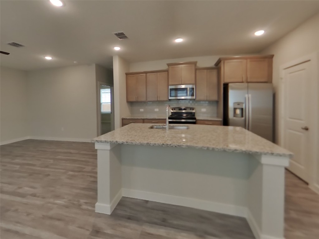 609 Foxtail Agave Street Leander, TX 78641 - Photo 5 of 29 a kitchen with stainless steel appliances granite countertop a sink a stove a refrigerator a microwave and white cabinets