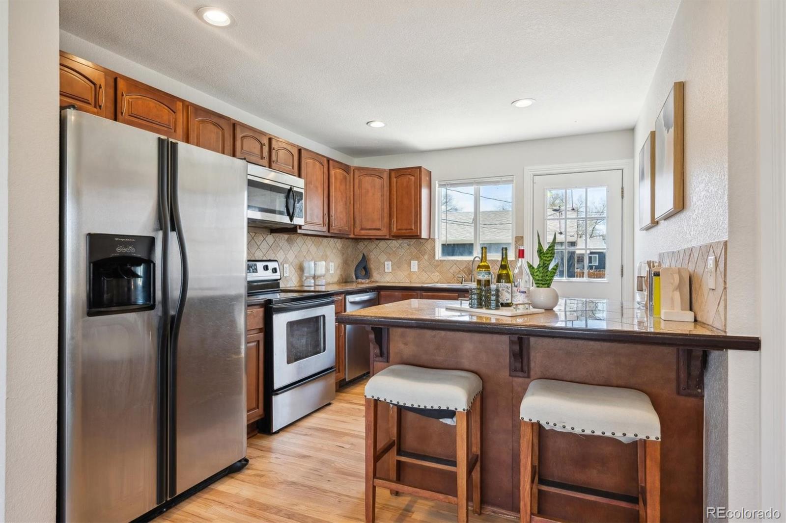 2285 Fulton Street Aurora, CO 80010 - Photo 4 of 22 a kitchen with stainless steel appliances granite countertop a stove refrigerator sink and cabinets