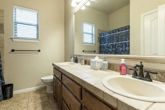 a bathroom with a granite countertop sink a toilet and a mirror
