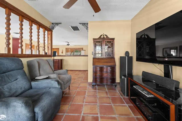 a living room with furniture a flat screen tv and a refrigerator