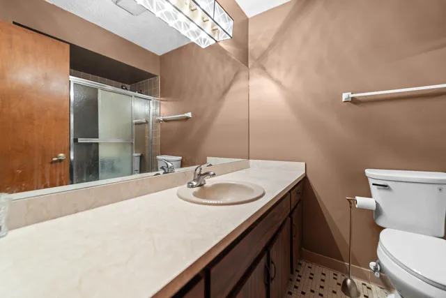 a bathroom with a granite countertop sink a toilet and a mirror