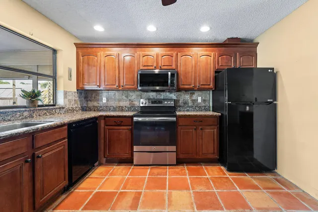 a kitchen with stainless steel appliances granite countertop a refrigerator and a sink