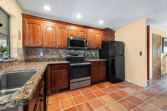 a kitchen with stainless steel appliances granite countertop a refrigerator stove top oven a sink and dishwasher