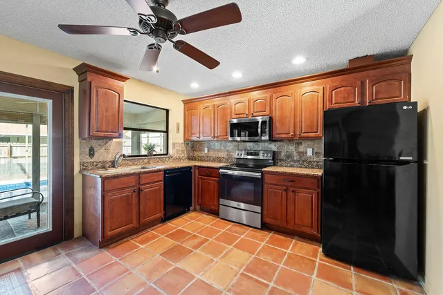 a kitchen with stainless steel appliances granite countertop a refrigerator a stove top oven and sink