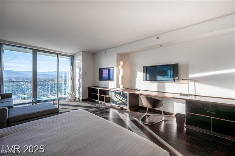 4381 West Flamingo Road, Unit 3303 Las Vegas, NV 89103 - Photo 5 of 37 Bedroom with floor to ceiling windows, built in study area, and wood finished floors