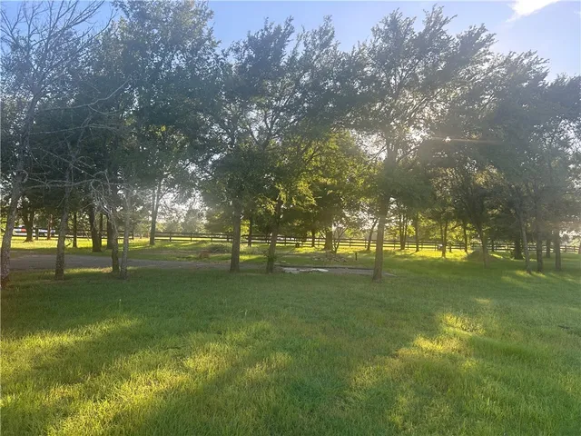 a yard with lots of green space and trees in the background