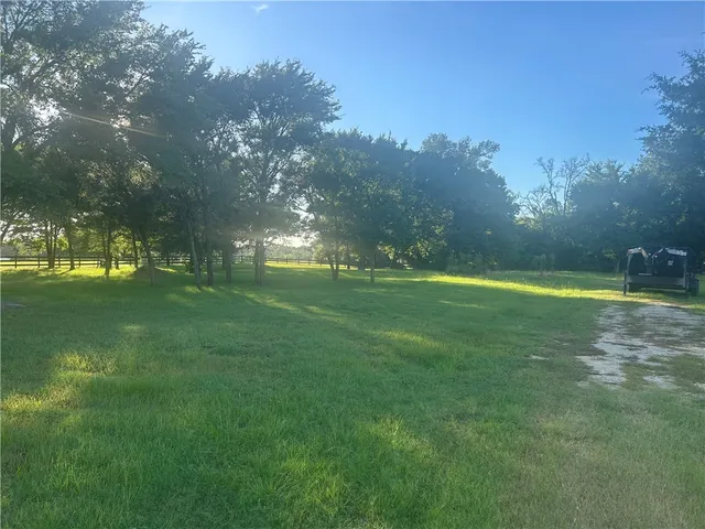 a yard with lots of green space and trees in the background