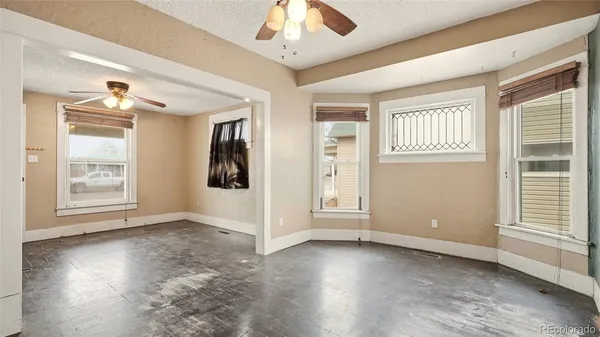 an empty room with wooden floor chandelier and windows