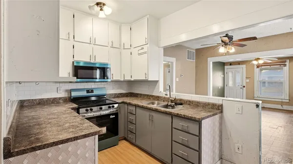 a kitchen with granite countertop a sink stainless steel appliances and white cabinets