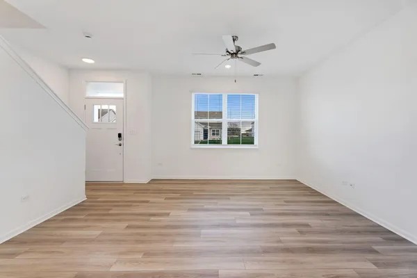 a view of an empty room with a window and wooden floor