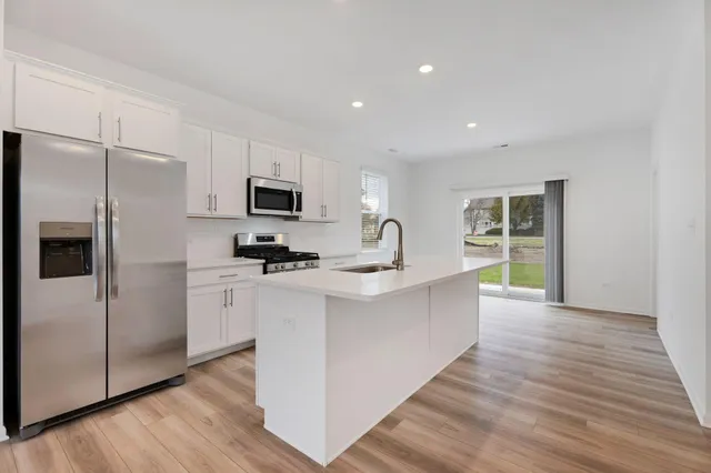 a large kitchen with a center island wooden floor stainless steel appliances and cabinets